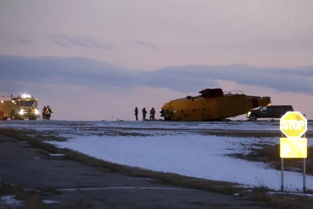 Emergency crews work around the wreckage of a downed CH-149 Cormorant search and rescue helicopter at 9 Wing Canadian Forces Base Gander, in Gander, Newfoundland and Labrador, Thursday, March 10, 2022. The Royal Canadian Air Force says there were six crew members on board the CH-149 search and rescue helicopter when it went down this afternoon. (Photo by Scott Cook/The Canadian Press via AP Photo)
