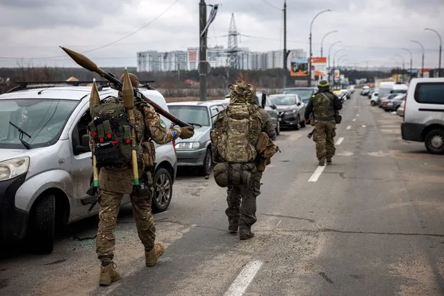 Ukrainian servicemen carry rocket-propelled grenades and sniper rifles as they walk towards the city of Irpin, northwest of Kyiv, on March 13, 2022. (Photo by Dimitar Dilkoff/AFP Photo)