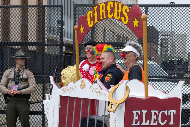 Denny Moriarty, Pat Spellacy, and Steve May, friends dressed up as clowns, pose with a police officer as another watches near the perimeter of the Republican National Convention in Milwaukee, Wisconsin on July 16, 2024. (Photo by Adrees Latif/Reuters)