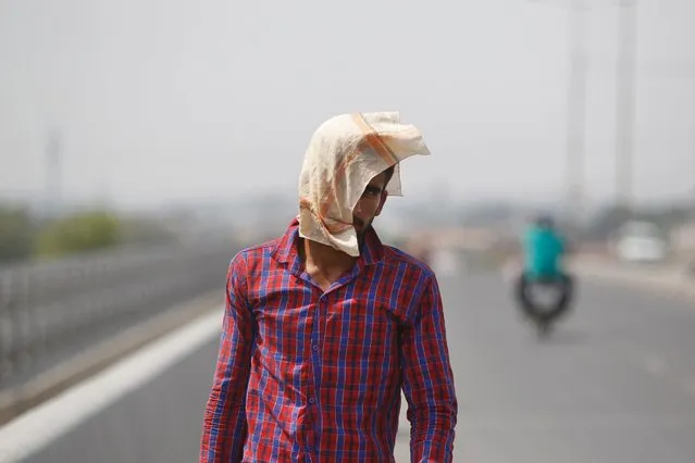 A man uses a cloth to protect himself from the sun and heat in Jammu, India, May 20, 2016. The prolonged heat wave this year has already killed hundreds and destroyed crops in more than 13 states. (Photo by Channi Anand/AP Photo)