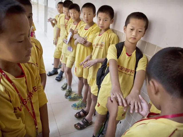 Young Chinese football players line-up to have their fingernails checked for cleanliness before training at the Evergrande International Football School near Qingyuan in Guangdong Province. (Photo by Kevin Frayer/Getty Images)