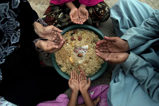 A family pray before breaking their fast during the Islamic month of Ramadan at a free food distribution point in Karachi, Pakistan, Wednesday, June 8, 2016. Muslims across the world are observing the holy fasting month of Ramadan, when they refrain from eating, drinking and smoking from dawn to dusk. (Photo by Shakil Adil/AP Photo)