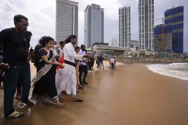 Human rights activists walk to offer flowers to the sea in remembrance of victims of Sri Lanka's civil war, at the ongoing anti government protest site in Colombo, Sri Lanka, Wednesday, May 18, 2022. Sri Lankan protesters lit flames and offered followers on Wednesday remembering thousands including ethnic Tamil civilians killed in the final stages of the country's long civil war, in the first-ever event where mostly majority ethnic Sinhalese openly memorialised the minority group. (Photo by Eranga Jayawardena/AP Photo)