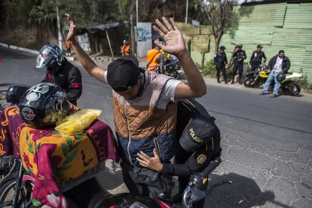 A police stops a motorcyclist to search him at a security checkpoint in the El Milagro area of the Mixco municipality on the outskirts of Guatemala City, Friday, January 17, 2020. Guatemala’s new president announced a state of alert for two municipalities with high crime rates to combat gang activity Friday, a measure that allows the deployment of military troops. (Photo by Oliver de Ros/AP Photo)