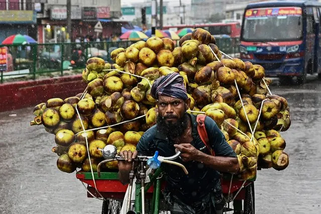 A man pulls a rickshaw-van loaded with sugar palms during a heavy rainfall in Dhaka on May 10, 2022. (Photo by Munir Uz Zaman/AFP Photo)