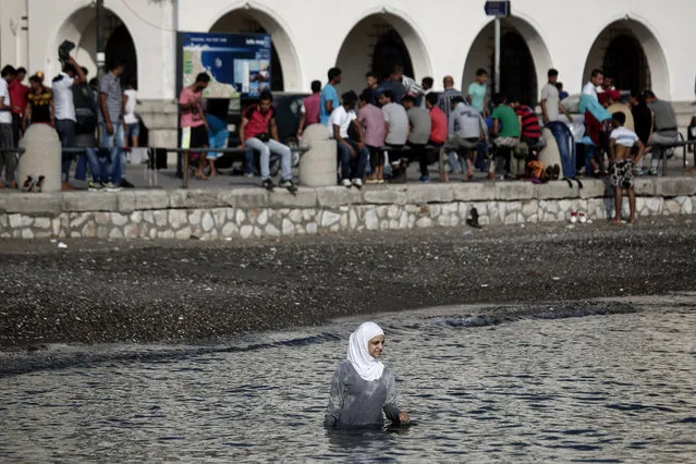 A migrant enters the sea as others wait for a registration procedure outside a police station in town of Kos at the southeastern island of Kos, Monday, August 10, 2015. (Photo by Yorgos Karahalis/AP Photo)