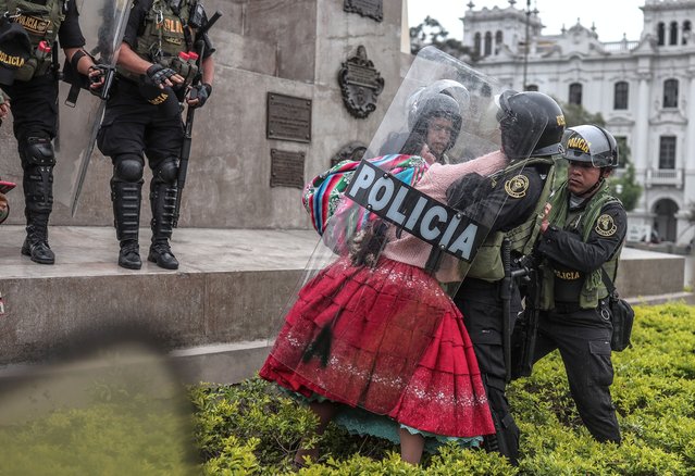 A demonstrator clashes with police during a protest in front of the Congress headquarters in Lima, Peru, 26 July 2023. A group of demonstrators gathered in front of the Peruvian Congress to protest against Parliament, while the configuration of its new board of directors was voted in a plenary session in which some deputies showed their claim that the country's president quits. (Photo by Aldair Mejia/EPA)