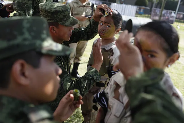 Soldiers apply camouflage paint to girls at the “The great strength of Mexico” army exhibition in Mexico City February 20, 2012. The exhibition is part of celebrations for the country's Army Day and Air Force Day, local media reported. (Photo by Tomas Bravo/Reuters)