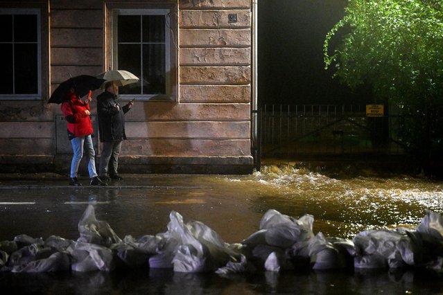 Local residents take photos on their mobile phones as water from the Biala river come to the city center in Glucholazy, southern Poland, on September 14, 2024 as Central Europe faces heavy rainfall expected to cause floods. Four people have died in Romania in floods triggered by Storm Boris, which has brought torrential rains and widespread disruption to central and eastern Europe, rescue services said. Since Thursday, September 12, 2024, swathes of Austria, the Czech Republic, Hungary, Romania and Slovakia have been hit by high winds and unusually fierce rains. (Photo by Sergei Gapon/AFP Photo)