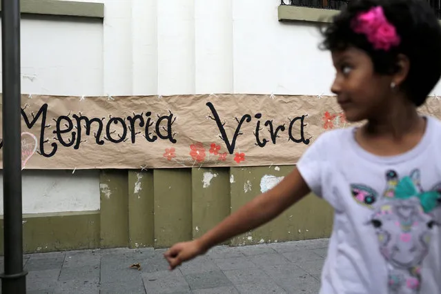 A girl plays in front of a banner that reads “Memory Alive” in memory of the victims of the armed conflict in Guatemala (1960-1996) during a protest against the army on National Army Day in Guatemala City, Guatemala, June 30, 2016. (Photo by Saul Martinez/Reuters)