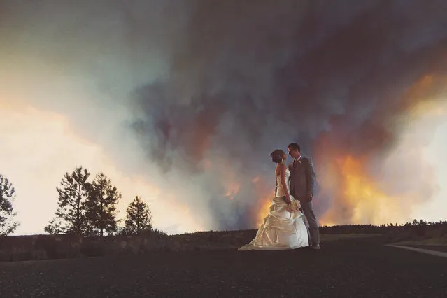 Wedding photographer, Josh Newton, has managed to turn a natural disaster into an amazing photo shoot opportunity. On June 7, 2014 Michael Wolber and April Hartley were getting ready to walk down the aisle in Rock Springs Ranch, Bend, Oregon, USA when firefighters alerted them to nearby wildfires gaining momentum and instructed them to flee to a safer location. Instead of leaving immediately, the wedding coordinator talked the firemen into letting the couple get married if they shortened the ceremony. (Photo by Josh Newton/IMP)
