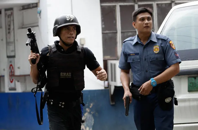 Policemen hold their weapons as they take up position, after a fellow policeman, who is high on drugs according to a police officer, run berserk at Manila Police Department in Manila, Philippines July 3, 2016. PO1 Vincent Paul Bulacan Solares, whose station assignment has yet to be determined, reportedly fired his gun at the second floor of the MPD headquarters past 3:00 p.m. This resulted in a 15-minute lockdown, radio reports said. He was arrested around 3:30 p.m. Solares reportedly made a scene while running amok and tried to shoot his fellow police officers. (Photo by Czar Dancel/Reuters)