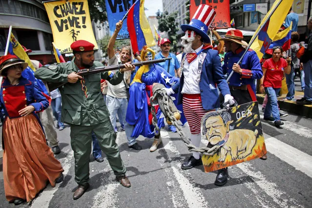 In this Monday, August 14, 2017 photo, government supporters perform a parody involving a Venezuelan militia up against Uncle Sam, a personification of the U.S government, during an anti-imperialist march to denounce Trump's talk of a “military option” for resolving the country's political crisis, in Caracas, Venezuela. (Photo by Ariana Cubillos/AP Photo)