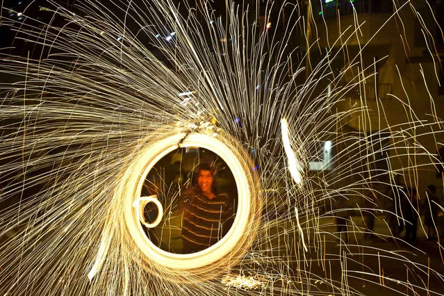 A Palestinian youth plays with a homemade sparkler after breaking his fast on the second day of the Muslim holy fasting month of Ramadan in the West Bank city of Ramallah, Monday, June 30, 2014. Muslims throughout the world are celebrating the holy month of Ramadan, where observants fast from dawn till dusk. (Photo by Muhammed Muheisen/AP Photo)