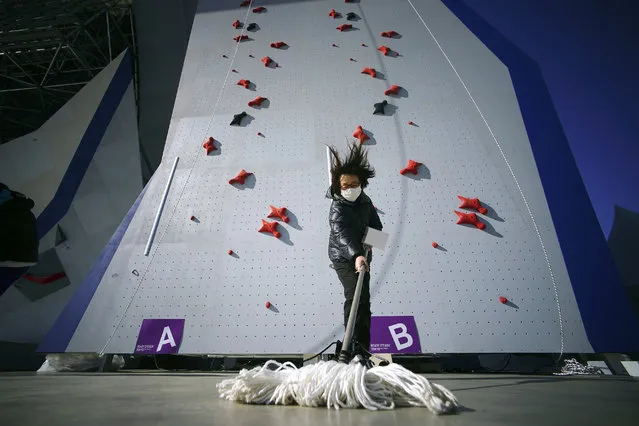 A Tokyo 2020 Olympic Games Organizing staff mops the floor in front of the climbing wall in the test event of Speed Climbing in preparation for the Tokyo 2020 Olympic Games at Aomi Urban Sports Park Friday, March 6, 2020, in Tokyo. The recent outbreak of the coronavirus has forced them to cancel or postpone several. But they allowed a sport climbing event on Friday to go ahead, with a few restrictions: like the absence of elite athletes. (Photo by Eugene Hoshiko/AP Photo)