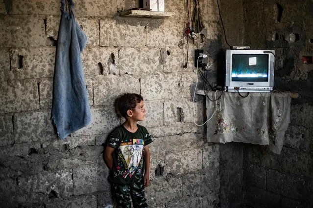 A Syrian boy, displaced with his family from Deir Ezzor, watches inside the damaged building where she is living in Syria's northern city of Raqa on June 18, 2022. (Photo by Delil Souleiman/AFP Photo)