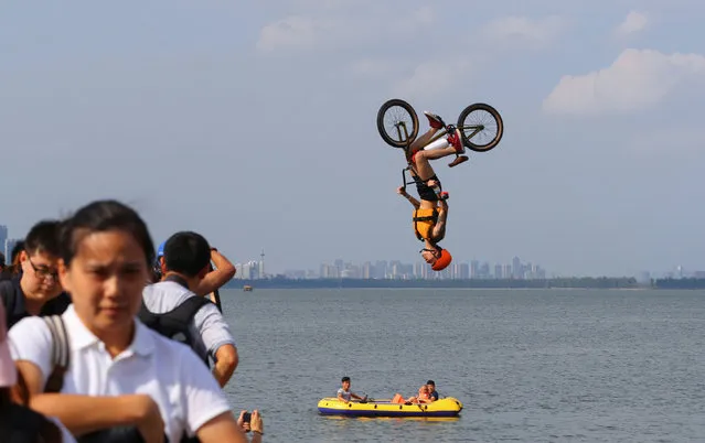 A man performs a BMX bicycle trick as he jumps into East Lake in Wuhan, Hubei Province, China August 19, 2017. (Photo by Reuters/China Stringer Network)