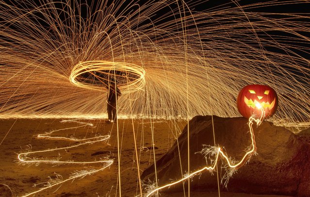 Halloween themed light painting on the beach at Clacton-on-the-Sea in Essex, UK on October 27, 2023. Burning steel wool was spun around and sparklers were used by Kevin Jay and Nigel Cox during a 52-second exposure with a pumpkin lit up with a LED light. (Photo by Kevin Jay/Picture Exclusive)