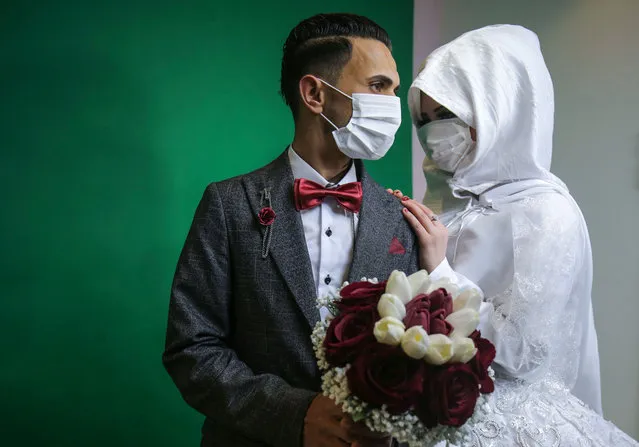 Palestinian groom Mohamed abu Daga and his bride Israa wear face masks amid the COVID-19 epidemic, during a photoshoot at a studio before their wedding ceremony in Khan Yunis in the southern Gaza Strip, on March 23, 2020. Authorities in Gaza confirmed on March 22 the first two cases of novel coronavirus, identifying them as Palestinians who had travelled to Pakistan and were being held in quarantine since their return, as the United Nations warned of potential disastrous outcomes to an outbreak given the high poverty rates and weak health system in the coastal strip, under Israeli blockade since 2007. (Photo by Said Khatib/AFP Photo)