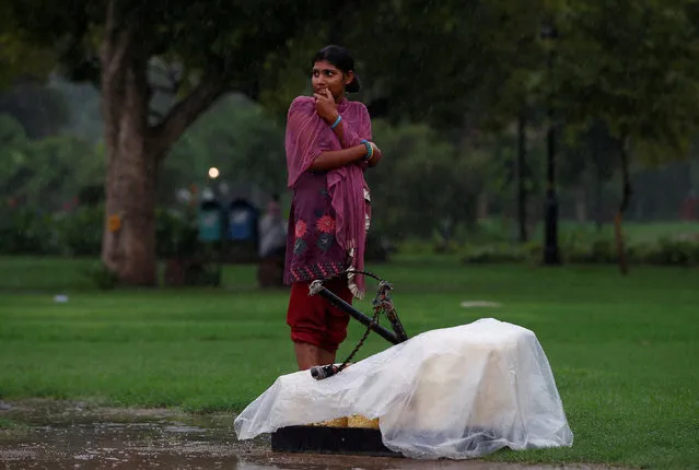 A girl stands next to her stall of snacks as it rains in New Delhi, India August 1, 2016. (Photo by Adnan Abidi/Reuters)