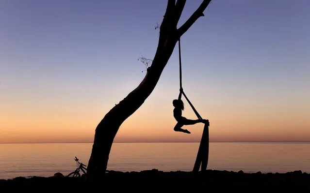 A woman does acrobatics with a ribbon on Banos del Carmen beach at dawn in Malaga, southern Spain, early morning 03 May 2020. Spain began a de-escalation phase amid coronavirus outbreak allowing adults go out home daily with restrictions. Adults are allowed to do exercise and go out for a walk from 6 to 10 am and 8 to 11 pm. Old people can go out for a walk from 10 am to 12 pm and 7 pm to 8 pm and under-14 children from 12 pm to 7 pm. Spain is under a lockdown to avoid the spreading of pandemic of the COVID-19 disease caused by the SARS-CoV-2 coronavirus. (Photo by Jorge Zapata/EPA/EFE)