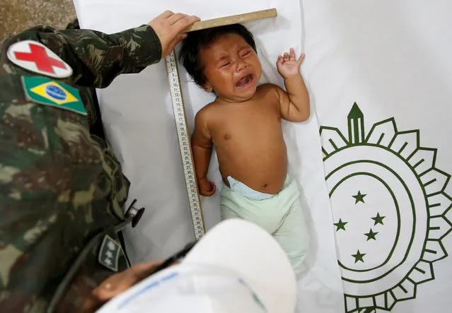 A Brazilian Army soldier gives medical attention to an indigenous baby during a joint military training for humanitarian actions with Colombian, U.S and Peruvian soldiers, in Tabatinga, Brazil November 09, 2017. (Photo by Leonardo Benassatto/Reuters)