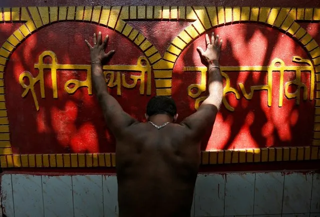 A Hindu man touches a wall of a temple as he offers prayers after taking a dip in the river Ganges in Kolkata, India, August 25, 2016. (Photo by Rupak De Chowdhuri/Reuters)