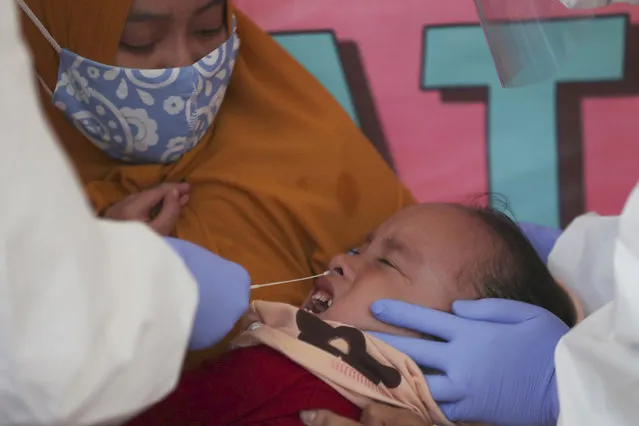 Health workers take a nasal swab sample from a girl during public testing for the new coronavirus conducted in Jakarta, Indonesia Monday, June 15, 2020. (Photo by Achmad Ibrahim/AP Photo)