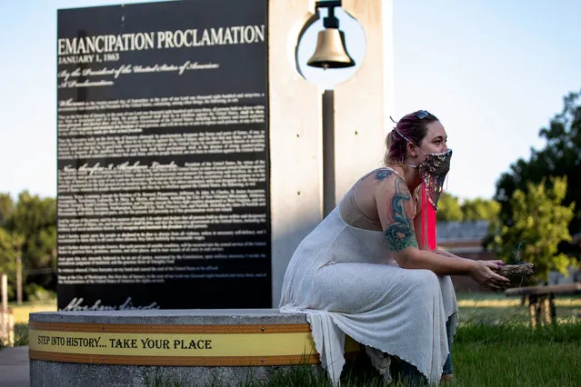 A woman in a mask burns a smudge stick as she sits near the Emancipation Proclamation sign as demonstrators gather to honor the fifteenth anniversary of the death of Sandra Bland behind the George Washington Carver Museum, Cultural and Genealogy Center on July 13, 2020, in Austin, Texas. Sandra Bland, a Black woman who died in 2015 while in police custody after an alleged traffic violation in Texas, was found dead in her Waller County jail cell three days after being arrested in 2015. Austin Mayor Steve Adler declared July 13, Sandra Bland Day in 2019. (Photo by Montinique Monroe/Getty Images)
