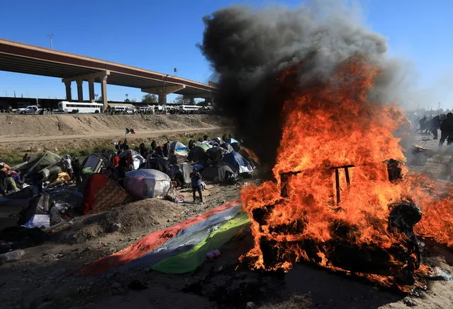 Belongings burn as Mexican authorities attempt to enforce an eviction at a migrant encampment, in Ciudad Juarez, Mexico, 27 November 2022. Migrants and authorities clashed at the banks of the Rio Grande River where migrants had set up tents near the border with the United States. (Photo by Luis Torres/EPA/EFE)