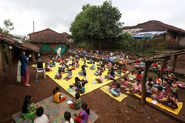 Children, who have missed their online classes due to a lack of internet facilities, maintain a safe distance as they listen to pre-recorded lessons over loudspeakers after schools were closed following the coronavirus outbreak, in Dandwal village in the western state of Maharashtra, India, July 28, 2020. (Photo by Prashant Waydande/Reuters)