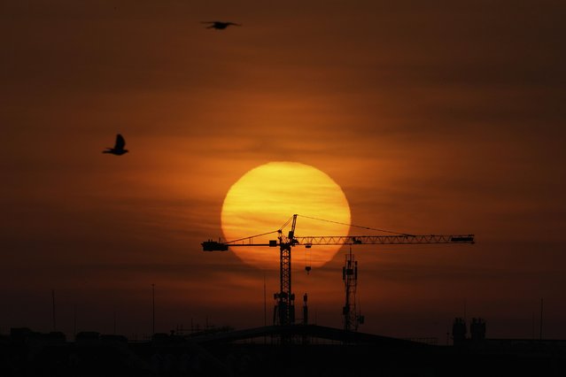 The sun rises behind a construction crane in Lisbon, Wednesday, April 9, 2025. (Photo by Armando Franca/AP Photo)