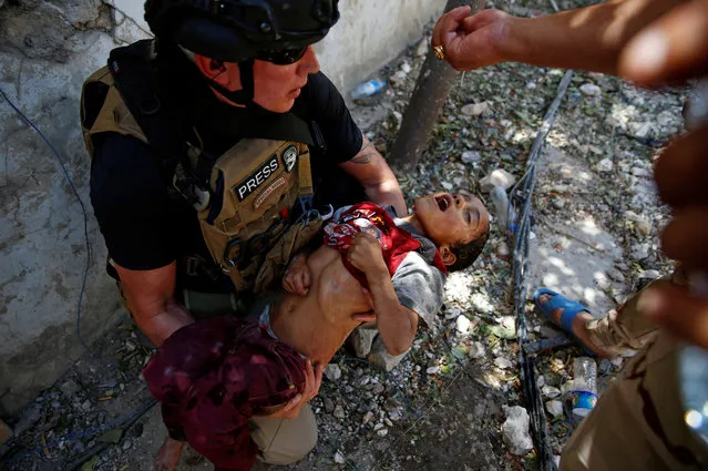 Iraqi soldiers from 9th Armoured Division give drops of water to a dehydrated child rescued earlier by soldiers at the frontline, during the ongoing fighting between Iraqi forces and Islamic State militants near the Old City in western Mosul, Iraq June 13, 2017. (Photo by Erik De Castro/Reuters)
