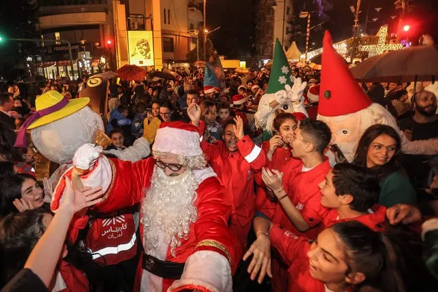 Revelers celebrate during the ceremony of the lighting of the Christmas tree in Sassine Square in the Ashrafieh district of Lebanon's capital Beirut on December 7, 2022. (Photo by Anwar Amro/AFP Photo)