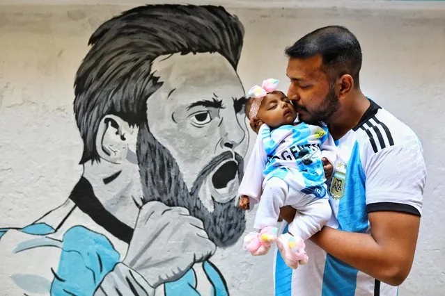 An Argentina fan kisses his daughter in front of a graffiti ahead of FIFA World Cup Qatar 2022 in Dhaka, Bangladesh on November 18, 2022. (Photo by Mohammad Ponir Hossain/Reuters)