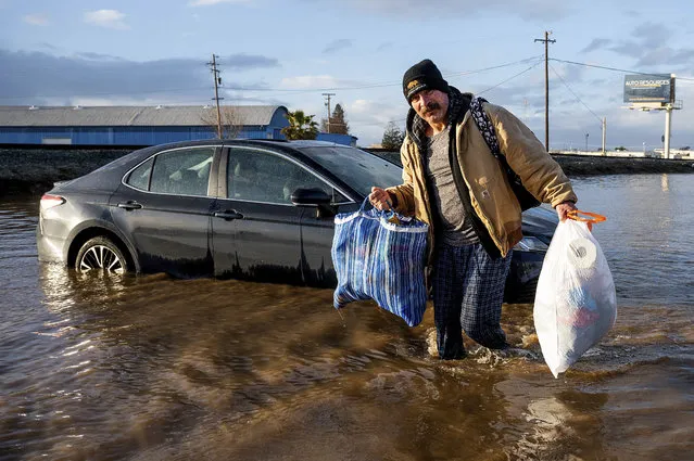 Jesus Torres carries belongings from his flooded Merced, Calif., home on Tuesday, January 10, 2023. (Photo by Noah Berger/AP Photo)