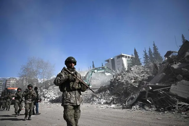 Turkish soldiers patrol next to collapsed buildings in Kahramanmaras on February 13, 2023, as rescue teams continue to search for victims and survivors, after a 7.8 magnitude earthquake struck the border region of Turkey and Syria. - The death toll from a catastrophic earthquake that hit Turkey and Syria climbed above 35,000 on February 13, 2023, with search and rescue teams starting to wind down their work. (Photo by Ozan Kose/AFP Photo)