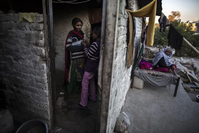 Girls talk to each other in their one-room shack while their grandmother sits outside, in a Christian slum in Islamabad December 4, 2014. (Photo by Zohra Bensemra/Reuters)