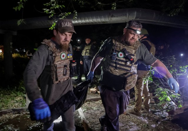 Rescuers carry the body of a person killed in a Russian missile strike, at a site of a residential building which was hit in the strike, amid Russia's attack on Ukraine, in Kharkiv, Ukraine on May 31, 2024. (Photo by Sofiia Gatilova/Reuters)