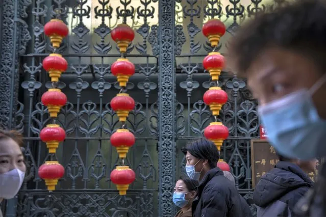 People wearing face masks walk past rows of lanterns at a tourist shopping street in Beijing, Tuesday, February 28, 2023. (Photo by Mark Schiefelbein/AP Photo)