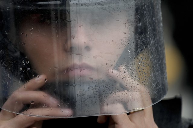 A police officer adjusts her helmet on the sidelines of an anti-government protest against food scarcity at soup kitchens and economic reforms proposed by President Javier Milei, in Buenos Aires, Argentina, May 7, 2024. (Photo by Natacha Pisarenko/AP Photo)