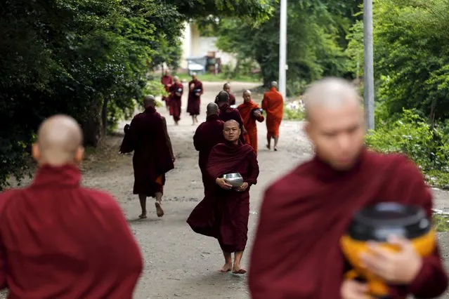 Buddhist monks walk with their alms bowls early morning outside the Masoyein monastery complex in Mandalay October 7, 2015. (Photo by Jorge Silva/Reuters)