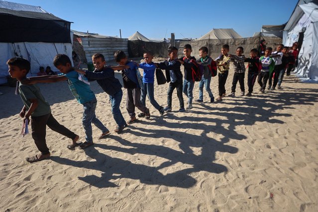 Palestinian pupils walk in a queue out of a tent used as a classroom at a school set up by the Mayasem Association for Culture with UNICEF support, at a displacement camp in the al-Qarara area of Khan Yunis in the southern Gaza Strip on October 7, 2025. The school dispenses classes to 1500 pupils on basic academic subjects in addition to arts such as drawing, music, and the traditional Tatreez embroidery as part of preserving Palestinian heritage. (Photo by Omar Al-Qattaa/AFP Photo)