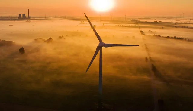 The morning mist is illuminated by the rising sun over fields and wind turbines near Sehnde, Germany, 19 August 2016. The Mehrum coal-fired power station is visible on the horizon. (Photo by Julian Stratenschulte/EPA)