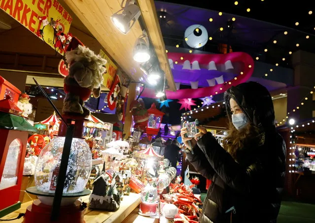 A woman wearing a face mask takes a picture of a display at a Christmas market in a shopping mall following an outbreak of the coronavirus disease (COVID-19) in Beijing, China on December 16, 2020. (Photo by Thomas Peter/Reuters)