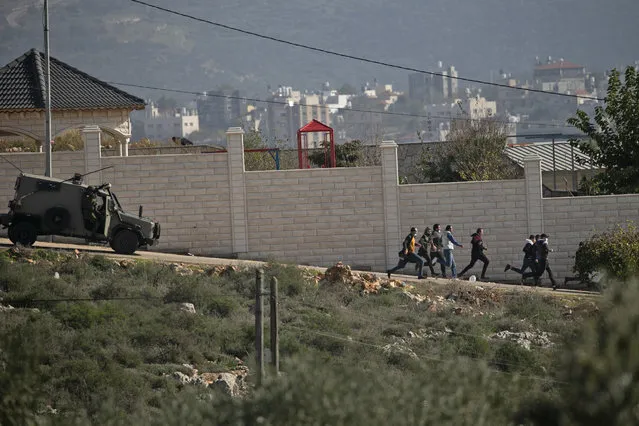 Palestinian protesters run away as an Israeli security vehicle chases after them amid clashes following a demonstration against the expansion of settlements in the town of Salfit, in the Israeli-occupied West Bank, on December 4, 2020. (Photo by Jaafar Ashtiyeh/AFP Photo)