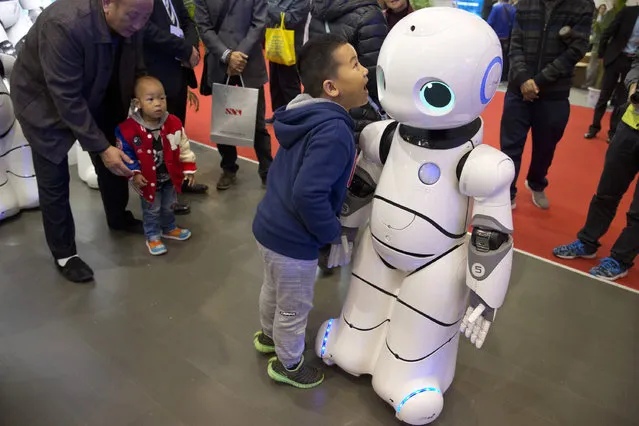 In this Friday, October 21, 2016 photo, a Chinese boy shouts into the Canbot, a companion robot, displayed during the World Robot Conference in Beijing. China is showcasing its burgeoning robot industry as it seeks to promote use of more advanced technologies in Chinese factories and create high-end products that redefine the meaning of “Made in China”. The Canbot can dance and respond to voice commands, while others can play badminton, sand cell phone cases and sort computer chips. (Photo by Ng Han Guan/AP Photo)