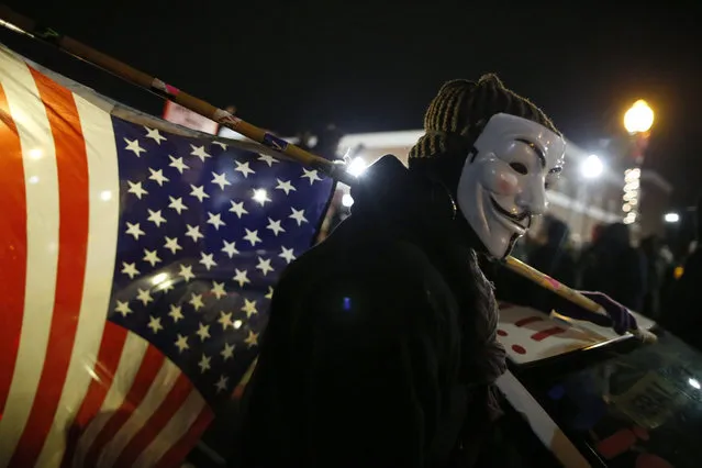 Ferguson, Missouri: A protester wearing a Guy Fawkes mask carries an American flag outside the Ferguson Police Department in Ferguson, Missouri, November 24, 2014. Missouri Governor Jay Nixon urged people in the St. Louis area to show respect and restraint following a grand jury's decision on whether to criminally charge a white police officer in the August fatal shooting of unarmed black teenager Michael Brown. (Photo by Jim Young/Reuters)