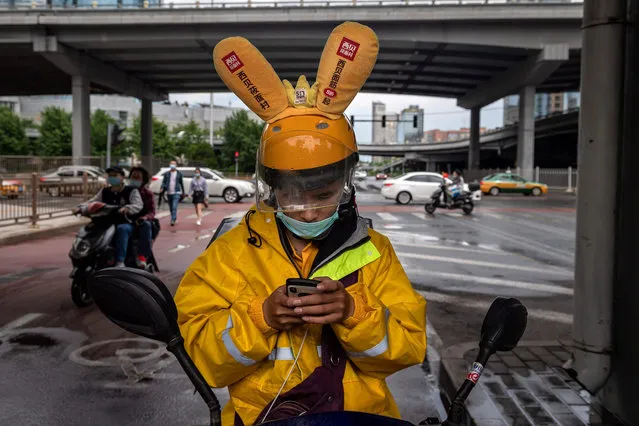 A delivery man looks at a map on his smartphone along a street in Beijing on May 25, 2020. (Photo by Nicolas Asfouri/AFP Photo)