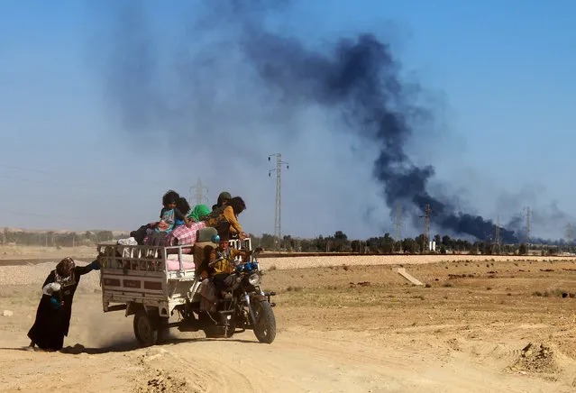 An Iraqi woman pushes a tricycle as government forces evacuate hundreds of Iraqis from the town of Heet in Iraq's Anbar province, to a safe area far from the battlefields where Iraqi troops are trying to retake the western town from the Islamic State (IS) group on April 4, 2016. Earlier in the week Iraqi security forces recaptured parts of Heet, which was one of the largest population centres in Anbar province still held by the Islamic State (IS) group, but other areas remain under jihadist control. (Photo by Moadh Al-Dulaimi/AFP Photo)